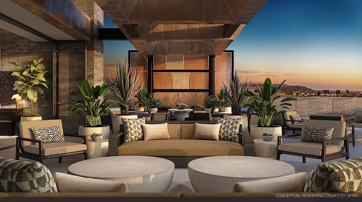 Luxury outdoor terrace lounge with contemporary RH furnishings, sculptural desert landscaping, and panoramic city and mountain views at sunset