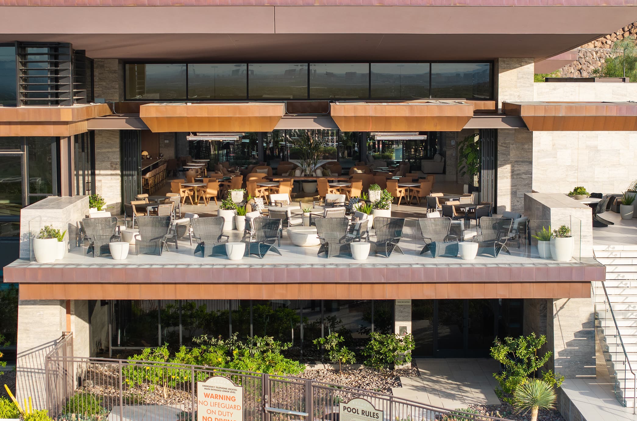 Modern luxury clubhouse with multi-level outdoor seating, open-air dining, and contemporary desert architecture.