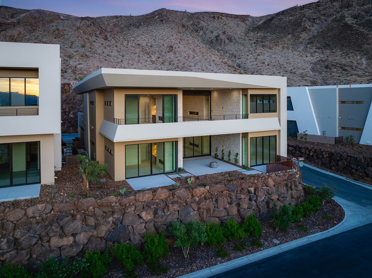 Modern two-story Canyon Residence with expansive balconies, floor-to-ceiling glass, and a private outdoor living area set against the desert mountainside.