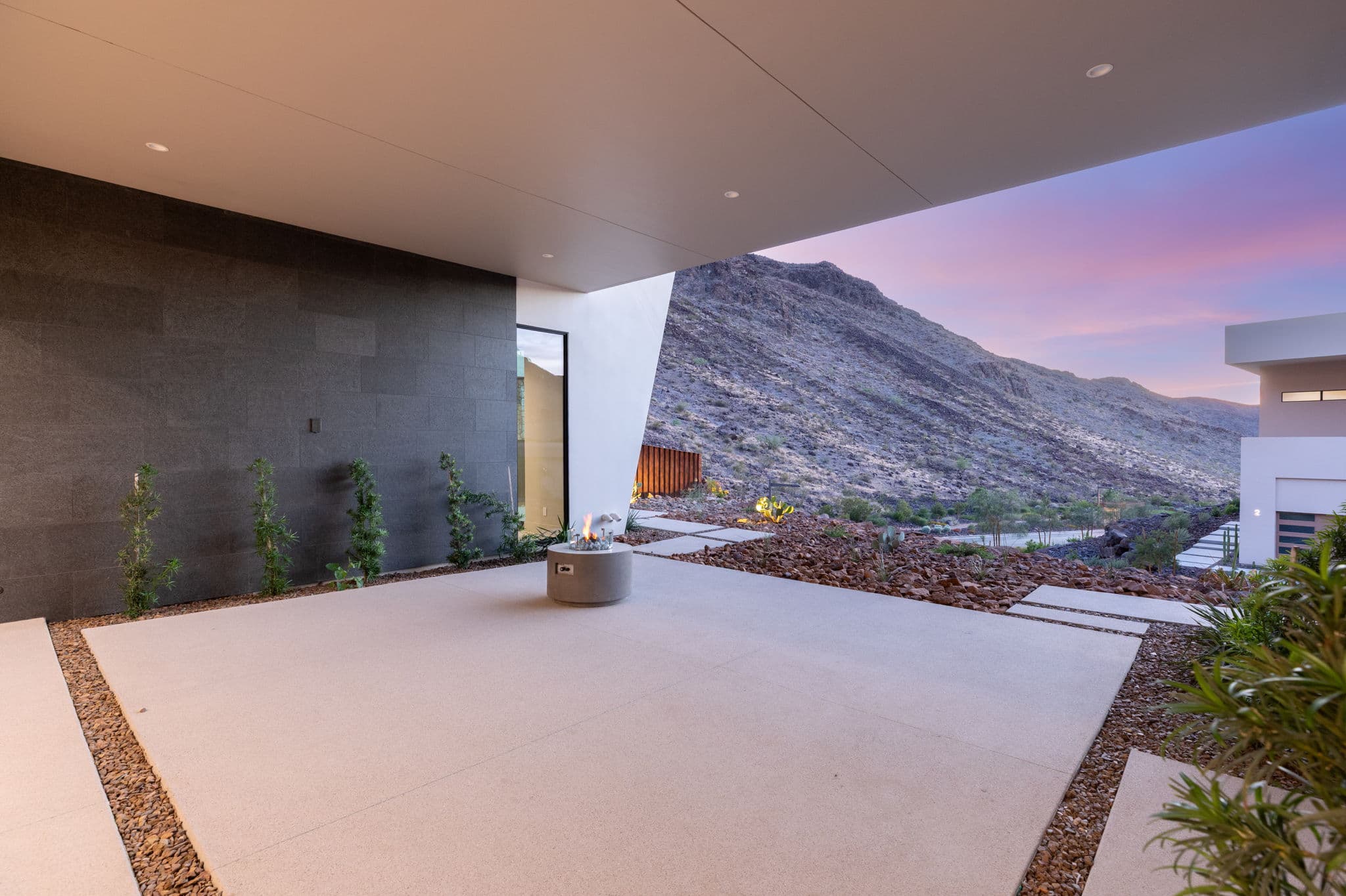 Covered outdoor terrace with modern fire feature and panoramic mountain views at sunset