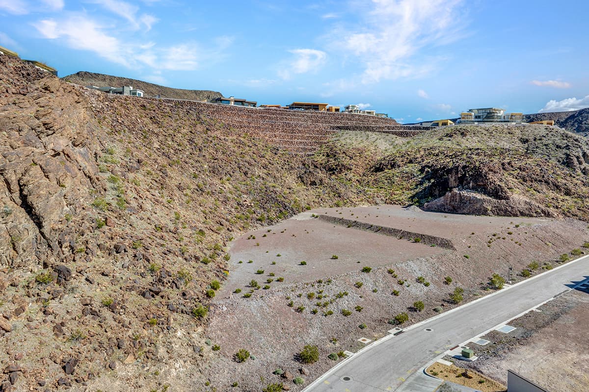 Aerial view of Homesite 58 at 22 Rockstream Drive, a terraced desert homesite framed by natural rock formations and neighboring contemporary homes at Ascaya.