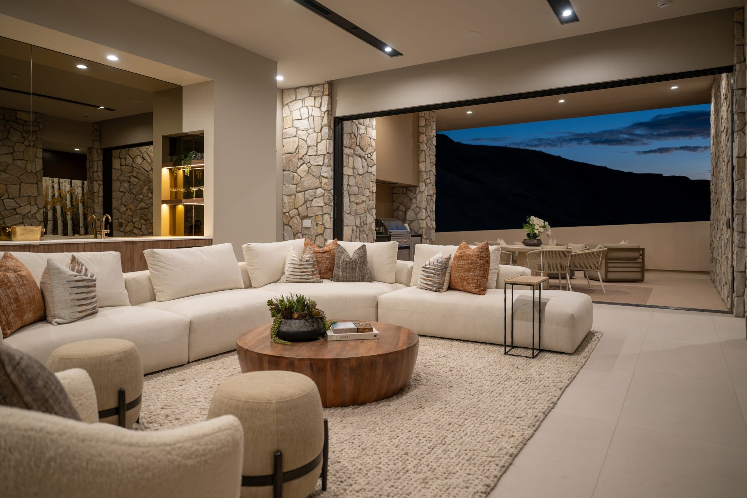 Luxury open-concept living room with a plush sectional, stone accents, and seamless indoor-outdoor entertaining space.