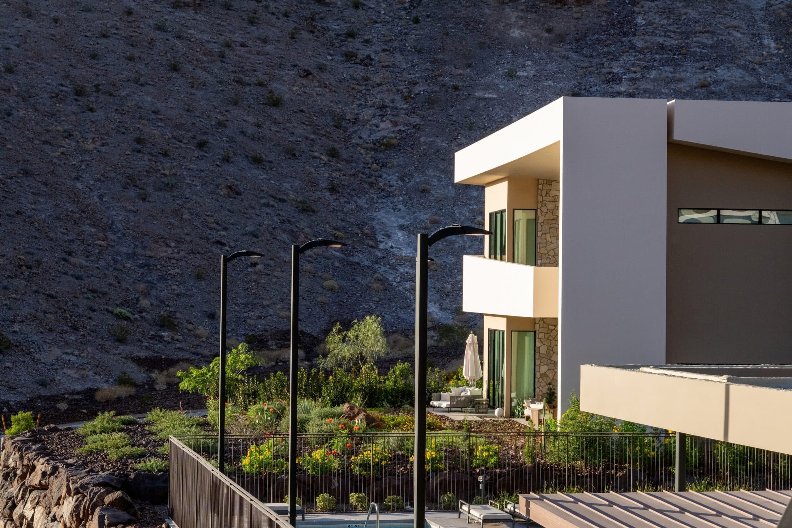 Modern luxury hillside residence with geometric architecture, landscaped gardens, and dramatic desert mountain surroundings.