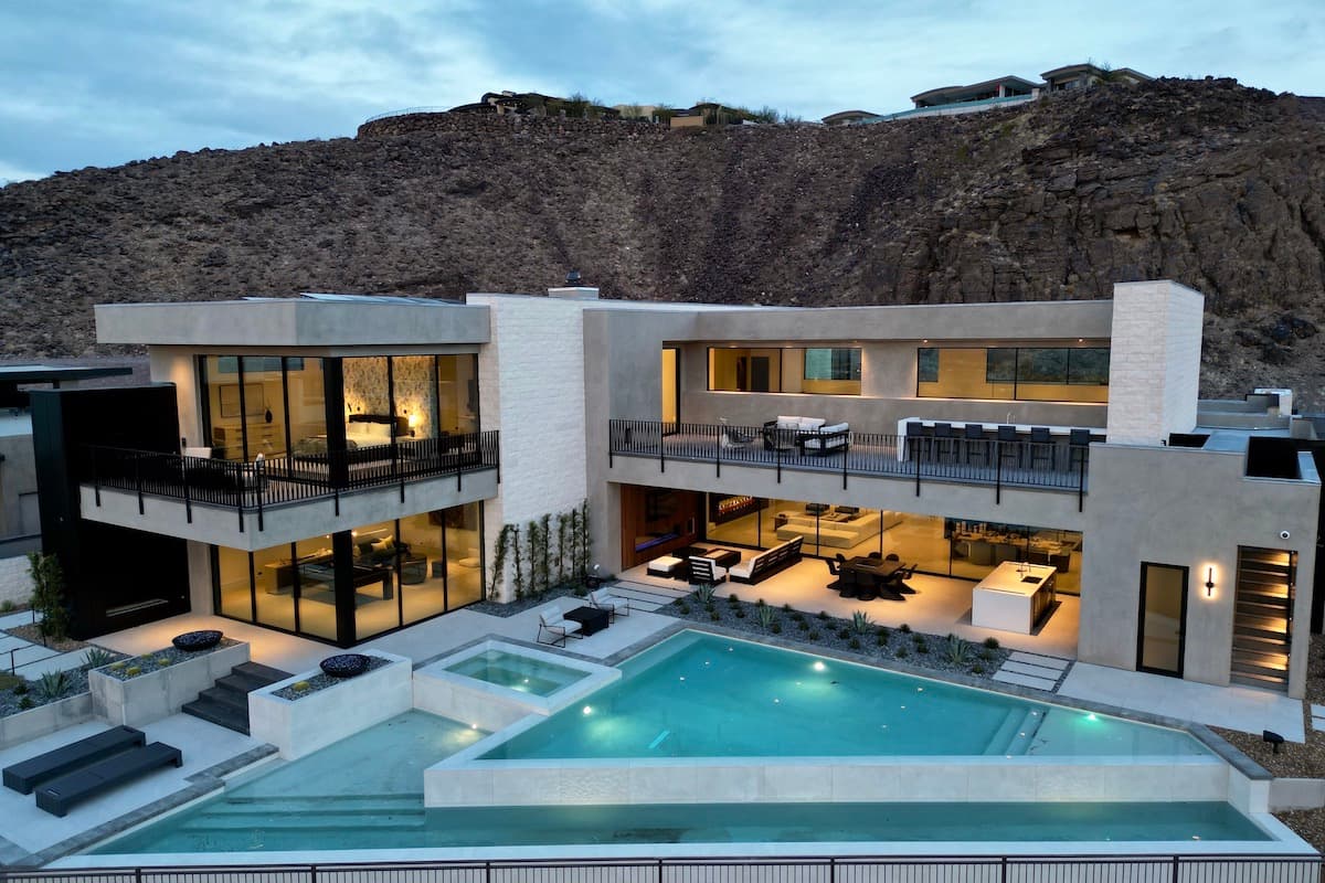 Modern clubhouse and pool area set against desert hills with lounge seating and landscaped grounds.