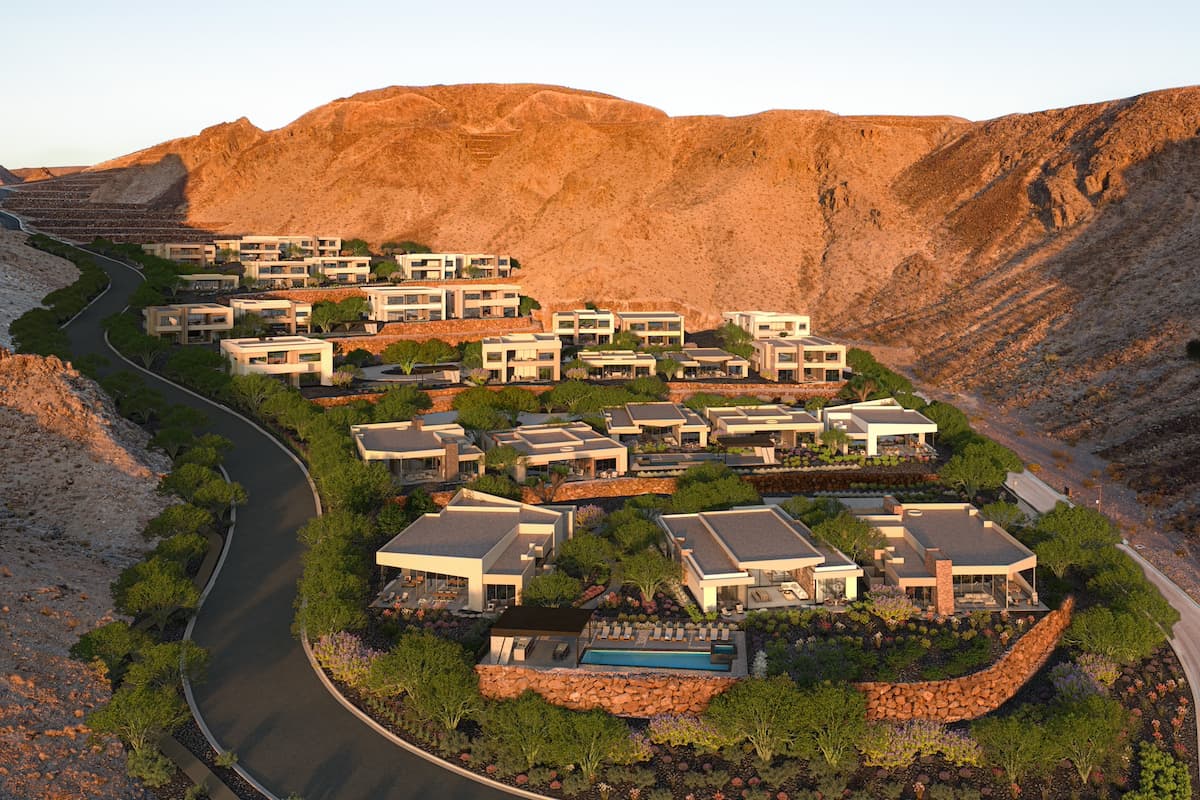 Terraced luxury homes nestled into a desert mountainside with landscaped greenery and winding road access.