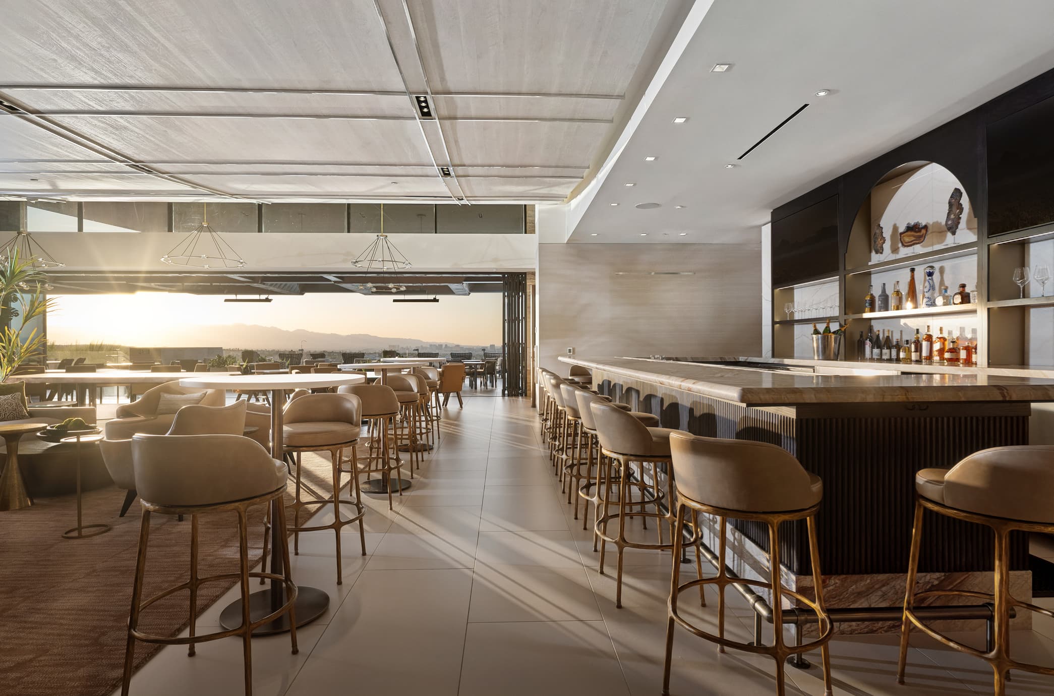 Modern luxury clubhouse bar and lounge with high-end seating, open-air design, and sunset mountain views.