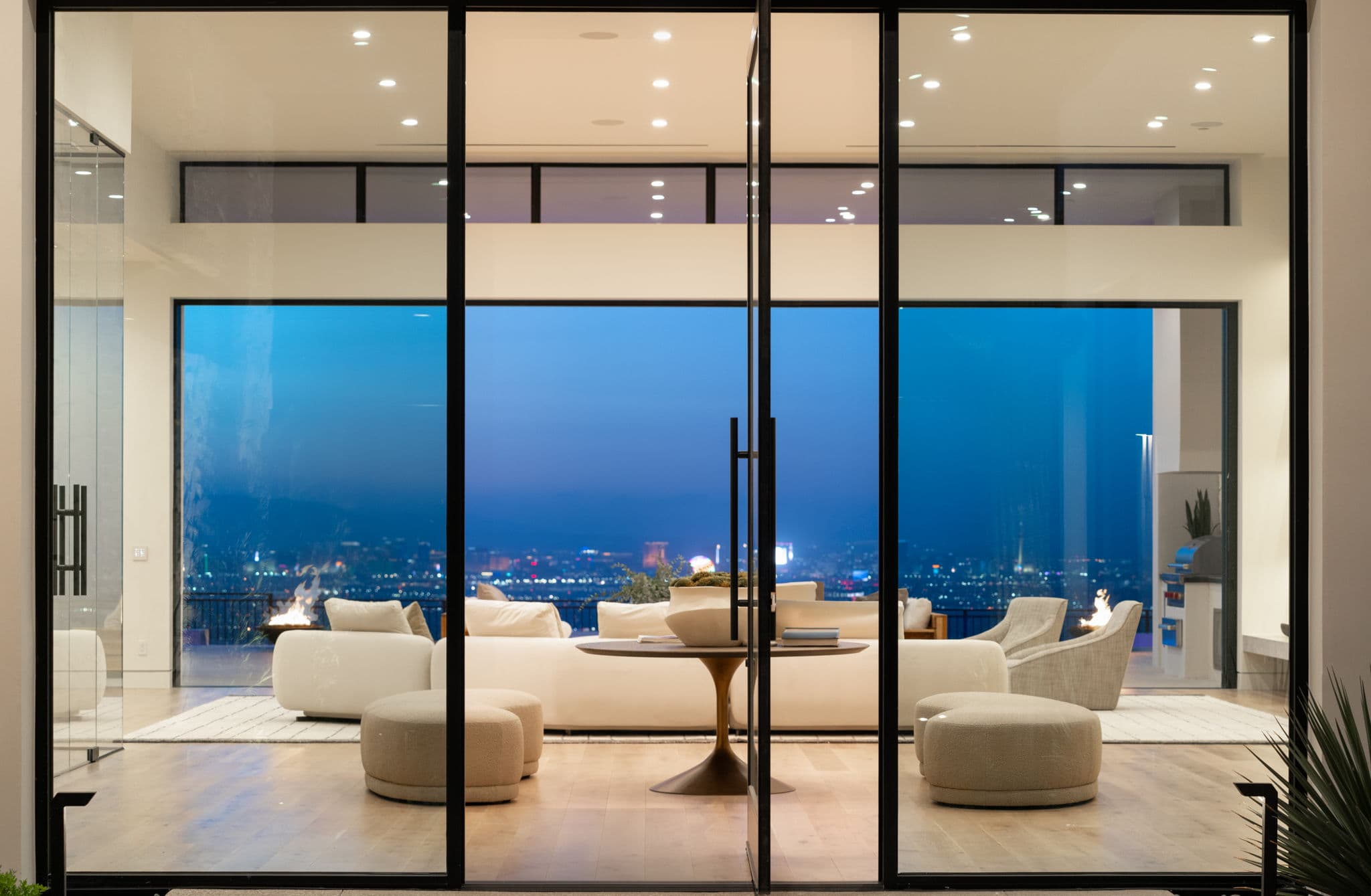 Luxury indoor-outdoor living space in Ascaya with floor-to-ceiling glass doors and Las Vegas Strip views at dusk