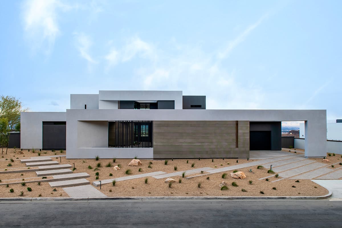Modern minimalist desert residence with flat roof, geometric design, neutral tones, and landscaped xeriscape front yard.
