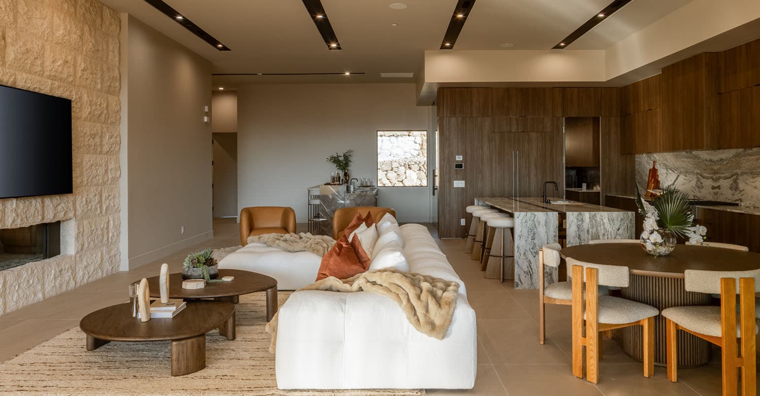 Modern open-concept living space with luxury kitchen, marble island, dining area, and contemporary living room in a high-end desert home.