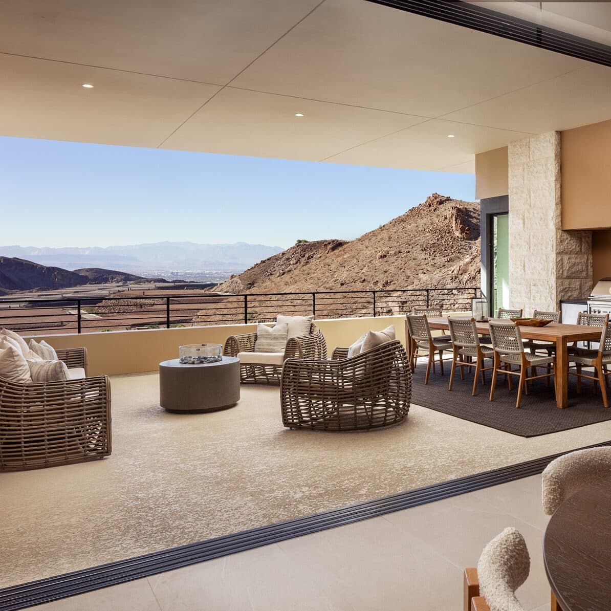 Luxury outdoor patio with modern lounge seating, dining area, and panoramic desert mountain views in a contemporary home.